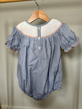 Load image into Gallery viewer, Blue checkered baby romper with white collar on a wooden hanger against a beige wall.
