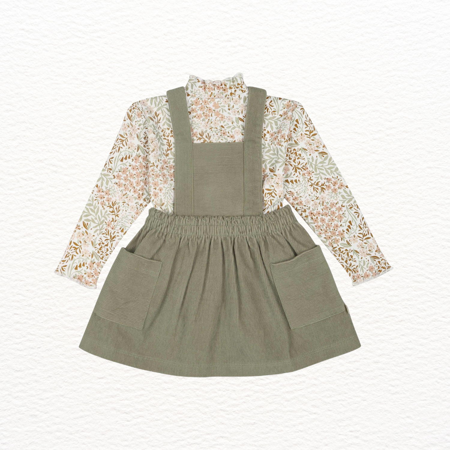 Green overall dress with floral blouse on a white background